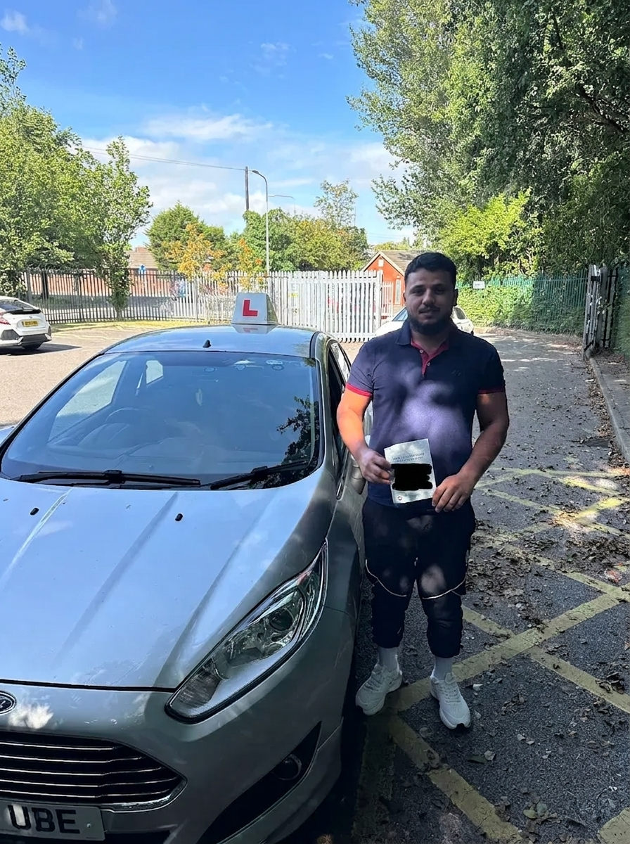 A learner holding their pass certificate beside the car